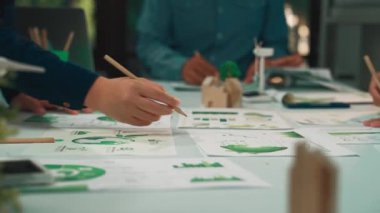 Değişik profesyonellerden oluşan bir grup, sürdürülebilirliği vurgulayan yenilikçi iş stratejileri geliştirmek için dinamik bir toplantıya katılıyor, belgeler ve çizelgeleri analiz ediyor. SACTR