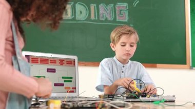 Kafkas akıllı çocuk kök teknoloji dersinde tornavida kullanarak ana tahtayı tamir ederken aynı zamanda gülümseyen öğrenci de dizüstü bilgisayar ekranı kodlu elektronik makineyi incelemek için birlikte çalışıyor. Pedagoji.