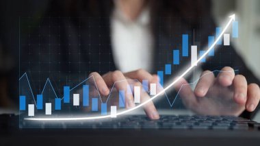 A business professional focuses on a laptop screen displaying digital graphs, highlighting growth trends and financial data, representing market insights and analytics. Copula