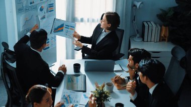 Akıllı yöneticinin üst görünümü, kurul ve kağıt arasındaki grafiği karşılaştırırken aynı zamanda başlangıç projesini iş toplantısında çeşitli takımlardan oluşan bir grupla birlikte planlıyor. Beyin fırtınası yapan ve birlikte çalışan takım. Müdürlük.