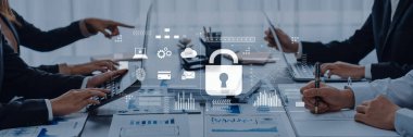 A professional team collaborates in an office setting, focusing on cybersecurity and data protection during a meeting. Digital graphics enhance the strategic discussion. Trope