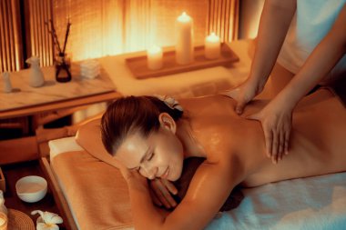 Beyaz kadın müşteri stres önleyici spa masajının keyfini çıkarıyor ve lüks otel ya da otelde sıcak mum ışığında güzellik teniyle eğleniyor. Sessiz.