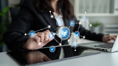 A business professional showcases interaction with digital icons on a tablet, symbolizing e-commerce and technology in a contemporary office setting. Tessel