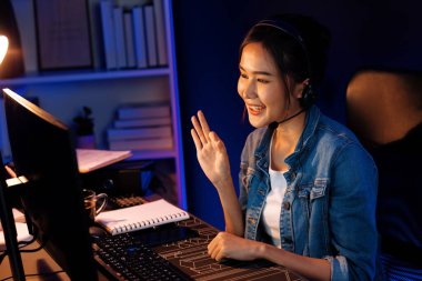 Sunucu kanalı Asyalı etkileyicisi canlı yayında konuşuyor. Sosyal medyada kulaklık takıyor, bilgisayar kaydı yapıyor, dinleyicileri selamlıyor ve Neon Modern Stüdyoları 'nda online olarak koçluk yapıyor. Taktik.