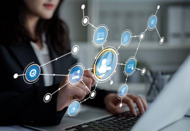 A business professional uses a laptop while interacting with digital network icons. This image captures technology, connectivity, and modern communication in a corporate setting. Crux