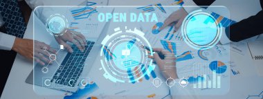 A business team collaborates on graphs and charts, utilizing an open data digital interface in a modern office setting to enhance their analytical strategies. Trope