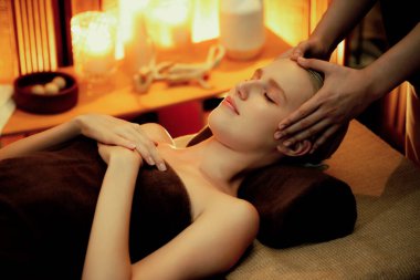 Beyaz kadın stres önleyici kafa masajı yapmaktan ve lüks otel veya otelde sıcak mum ışığında yüz güzelliği eğlencesi yapmaktan zevk alıyor. Sessiz.