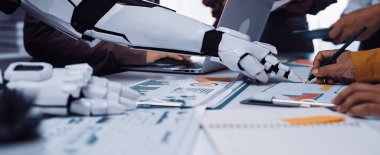 Gelecekçi bir robotik kol, iş birlikçi bir ofis ortamında insan eliyle meşgul olarak, teknolojinin proje planlama ve analizlerine entegrasyonunu gösteriyor. Noogenesis