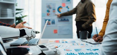 Profesyonellerin teknolojiyi kullanarak veri analizine giriştiği işbirlikçi bir ortamı tasvir eden modern bir ofis sahnesi. Robot bir kol gösterilir, yeniliği simgeler. Noogenesis