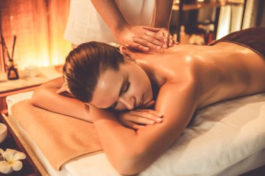 Beyaz kadın müşteri stres önleyici spa masajının keyfini çıkarıyor ve lüks otel ya da otelde sıcak mum ışığında güzellik teniyle eğleniyor. Sessiz.