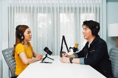 Gülümseyen radyo etkili sunucusu kulaklık takıyor kadın konuşmacı ile röportaj yapıyor sosyal medya internet sitesinden dinleyicilere bilgi paylaşıyor stüdyo kaydında sabah canlı yayın kanalı. İnfobahn.