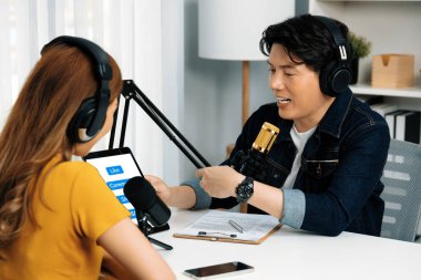 Gülümseyen radyo etkili sunucusu kulaklık takıyor kadın konuşmacı sosyal medya online canlı yayın kanalı ile röportaj yapıyor tablet ekranla konuşarak sabah stüdyo kaydındaki bağlantıyı paylaşıyor. İnfobahn.