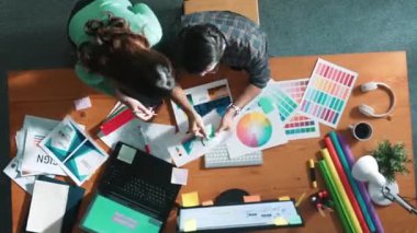 Akıllı tasarımcının renkli paletlerden renk seçmesine yardım ederken yukarıdan aşağı görünümü. Dizüstü bilgisayardan logoya bakarken birlikte çalışan ve planlayan iş adamlarının hava görüntüsü. Sempozyum.