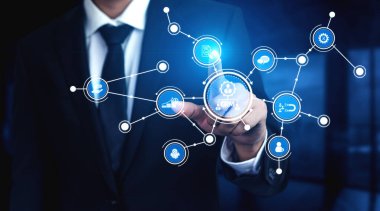 A businessman engages with an advanced virtual interface, showcasing digital icons that emphasize finance, communication, and analytics in a contemporary office setting. Tessel