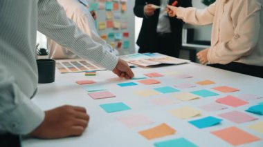 A dynamic office scene showing a diverse group of professionals engaged in a brainstorming session. Colorful sticky notes are spread across the table, capturing ideas. SACTR