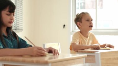 Zeki öğrenci sınıfta otururken öğretmenlerin sorularına cevap verir. Tahtaya bakarak ve ilköğretim sınıfına katılarak çeşitli çocuklar öğreniyor ve öğreniyor. Eğitim konsepti. Pedagoji.