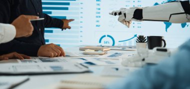 İş analizlerindeki teknoloji ve takım çalışmasını sembolize eden, insan eli ve robot kolun görsel verilerle etkileşime girdiği işbirlikçi bir toplantı sahnesi.