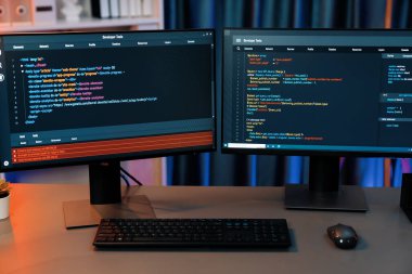 Bilgisayardaki programlama kodu masaüstü çalışma masasındaki iki ekranda akıllı web sitesi geliştirme kodlayıcı sisteminin neon ışık odasında veri teknolojisi çalıştırdığını gösteriyor. İnfobahn.