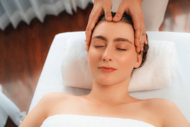 Kafkasyalı kadın stres önleyici kafa masajından ve lüks tatil beldesi ya da otel spa salonundaki modern ışık ortamında yüz güzelliği eğlencelerini şımartmaktan hoşlanıyor. Sessiz.