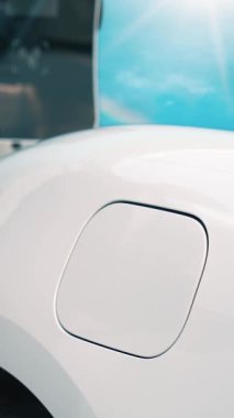 İlerici işadamı elektrikli arabayı tepe üzerindeki yolculuğunda şarj istasyonuyla dolduruyor. Temiz çevre için yenilenebilir enerji ile çalışan EV arabası. EV otomobilinden enerji sürdürülebilirliği kavramı.