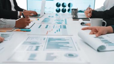 Diverse business professionals engage in a strategic meeting, analyzing charts and graphs on a modern office table, showcasing teamwork and data-driven insights. SACTR
