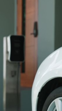 İlerici kadın evdeki elektrikli aracına şarj istasyonu fişi takıyor. EV otomobilleri çevreye yararlı temiz ve yeşil enerji kavramı sağlar.