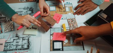 Değişik ellerin etkin bir şekilde bir tasarım oturumunda işbirliği yaptığı canlı ve ilgi çekici bir sahne, sergilenen kat planları, renkli örnekler ve malzeme örnekleri. SACTR