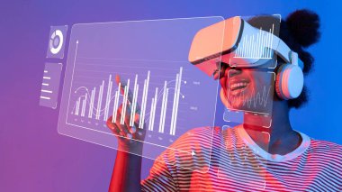 Neşeli genç bir kadın sanal gerçeklik dünyasını keşfediyor, renkli bir çalışma alanında etkileyici veri görselleştirmeleri ile etkileşime geçiyor, teknolojinin heyecanını vurguluyor. Raster.