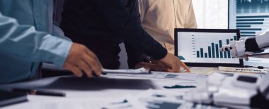 Bir iş ekibi, stratejik planlama ve performans geliştirme için teknolojiyi kullanırken, verileri grafikler ve grafikler kullanarak analiz ederek bir ofis ortamında işbirliği yapmaktadır.