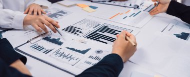 Bir konferans masası etrafında strateji ve içgörüleri tartışırken finansal raporları ve çizelgeleri analiz eden birkaç eli resmeden işbirlikçi bir iş görüşmesi sahnesi. SACTR