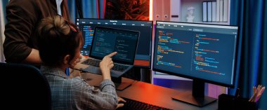 Modern ofisteki neon ışık odasında bilgi ağını gösteren dizüstü bilgisayarla iki ekranda veri çalıştıran akıllı web sitesi geliştirme kodlayıcı sistemini tartışan IT geliştiricilerinin ciddiyeti. İnfobahn.