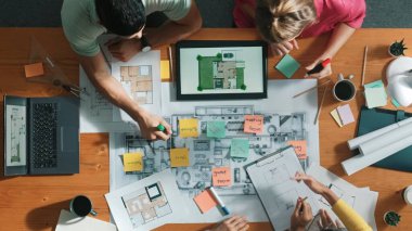 Akıllı mimar yazma fikrinin yukarıdan aşağı görüntüsü toplantı masasında şablon ve tablet bina inşaatı ile yapışkan notta. Yöneticinin not alıp paylaşma planını havadan izlemesi. Sempozyum.