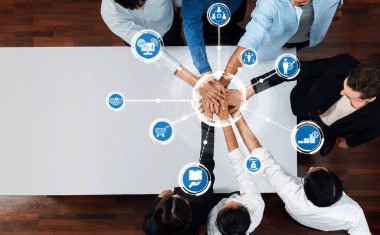 Aerial view of diverse professionals joining hands over a table, symbolizing collaboration, unity, and innovative teamwork in a business environment. Amity