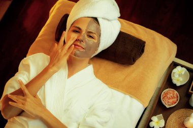 Kaplıca salonunun sakin atmosferi, üst düzey kadın müşteri sıcak mum ışığında kömür kömürü yüz kremi masajıyla kendini yenilemeye çalışıyor. Yüz bakımı ve güzellik konsepti. Sessiz.