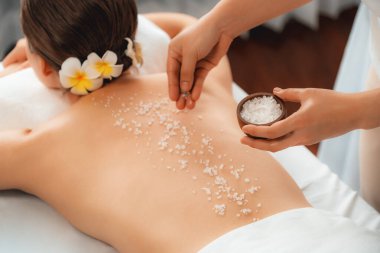 Lüks spa salonlarında sıcak mum ışığında cilt bakımı yaptıran kadın müşteri. Sağlık Spa vücut fırçasında tuz temizleme güzellik tedavisi. Sessiz.