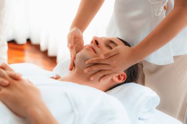 Beyaz adam stres önleyici kafa masajından ve lüks bir tatil beldesi veya otel spa salonundaki modern ışık ortamında yüz güzelliği eğlencelerini şımartmaktan hoşlanıyor. Sessiz.