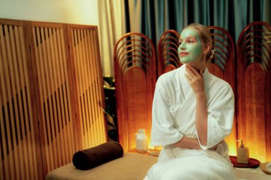 Kaplıca salonunun sakin atmosferi, kadın müşteri sıcak mum ve lüks yüz kremi masajıyla kendini yenileme zevkine kapılıyor. Yüz bakımı ve güzellik konsepti. Sessiz.