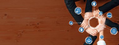 Hands of diverse individuals unite over a wooden table, symbolizing collaboration and strategy for business success, surrounded by icons of teamwork and planning efforts. Amity