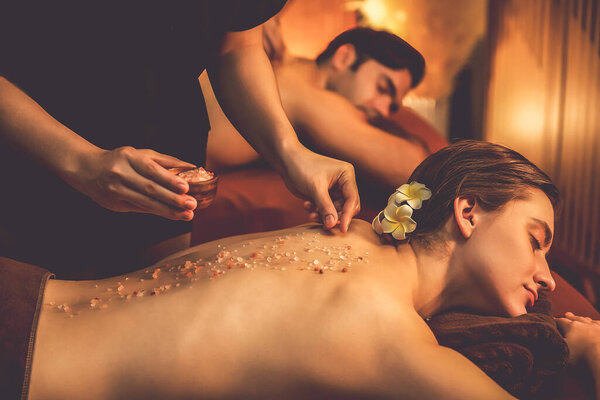Пара клиентов, проводящих пилинг в роскошном спа-салоне с теплым свечой окружающей среды. Косметическое лечение бальзамическим скрабом в Health spa scrub. Quiescent