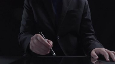 A businessman interacts with a digital tablet displaying glowing tax-related icons, illustrating modern financial management and technology integration in a sleek design. Qubit