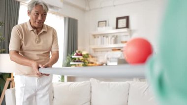 Yaşlı bir adam evde partneriyle top yuvarlama oyunu oynuyor, zihinsel ve fiziksel sağIık için el-göz koordinasyonu, odaklanma ve motor becerileri pratiği yapıyor. Sağlık hizmetleri konseptini engelliyor. Myrmidon.