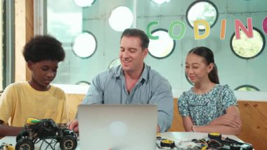 Yakışıklı öğretmen, sofrasında araba modeli ve panosu olan bir dizüstü bilgisayar kullanarak elektronik ekipmanı açıklıyor. Çok kültürlü çocuklar BTMM sınıfında araba modeli yapısını anlatırken öğretmenlerini dinlerler. Öğretim