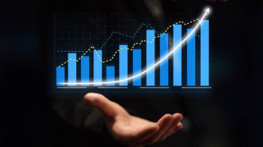 Businessman showcases a growth chart with blue bars and an upward trend, symbolizing financial progress and effective investment strategies in a digital environment. Copula