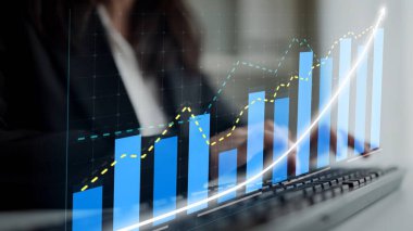 A business professional engages with statistical data on a screen, highlighting upward trends and growth in a modern office setting, symbolizing financial success and productivity. Copula