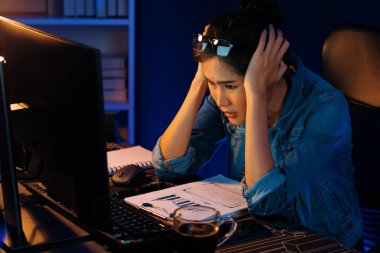 Stresli, genç, güzel Asyalı yaratıcı proje yaratıcısı sosyal medyayı araştırmak için bilgisayara bakıyor ve geceleri daha çok neon modern ofisin planlama kanalı stratejisine ulaşılıyor. Taktik.