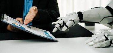 Bir insan ve robot bir iş toplantısına katılıyor, sunumlar ve belgeler aracılığıyla iletişim ve işbirliği sergiliyor. Teknoloji temaları için ideal. Haylazlık.