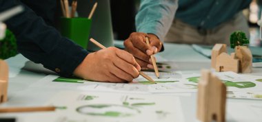 Çeşitli profesyonellerin elleri, yenilikçi çizimler ve modellerle dolu modern bir çalışma alanında sürdürülebilir çözümler arayarak işbirlikçi tasarım çalışmalarına giriştiler. SACTR