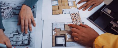 Mimari planlama üzerine dinamik bir işbirliği içinde olan iki birey, tasarım sürecinin yaratıcılığını gösteren çizimler ve planlarla çevrelenmiştir. SACTR