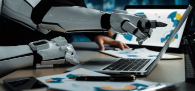 Yenilikçi çalışma alanlarında teknoloji ve takım çalışmasının yakınlaşmasını sembolize eden, dizüstü bilgisayarla uğraşan bir robotun modern ofis sahnesi. Noogenesis