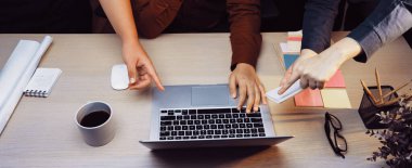 Bir grup profesyonel, bir yandan kahve ve etkili takım çalışması için renkli post-it notları üzerine fikirlerini paylaşırken, bir yandan da dizüstü bilgisayara odaklanan çağdaş bir ofis ortamında işbirliği yapıyor. SACTR